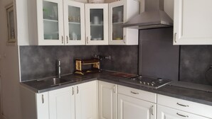 A kitchen with white cabinets, a stainless steel sink, a built-in stove, and a range hood. - SEASONAL RENTAL - LOWER VILLA (La Londe-Les-Maures)