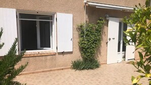 A building with a tiled patio, a window with white shutters, and a door. - SEASONAL RENTAL - LOWER VILLA (La Londe-Les-Maures)