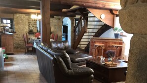 A rustic interior with a stone wall, wooden staircase, leather sofa, and a dining area with a table and chairs. -  Longére A Larmor-Plage, authentic charm of the stone. (Larmor-Plage)