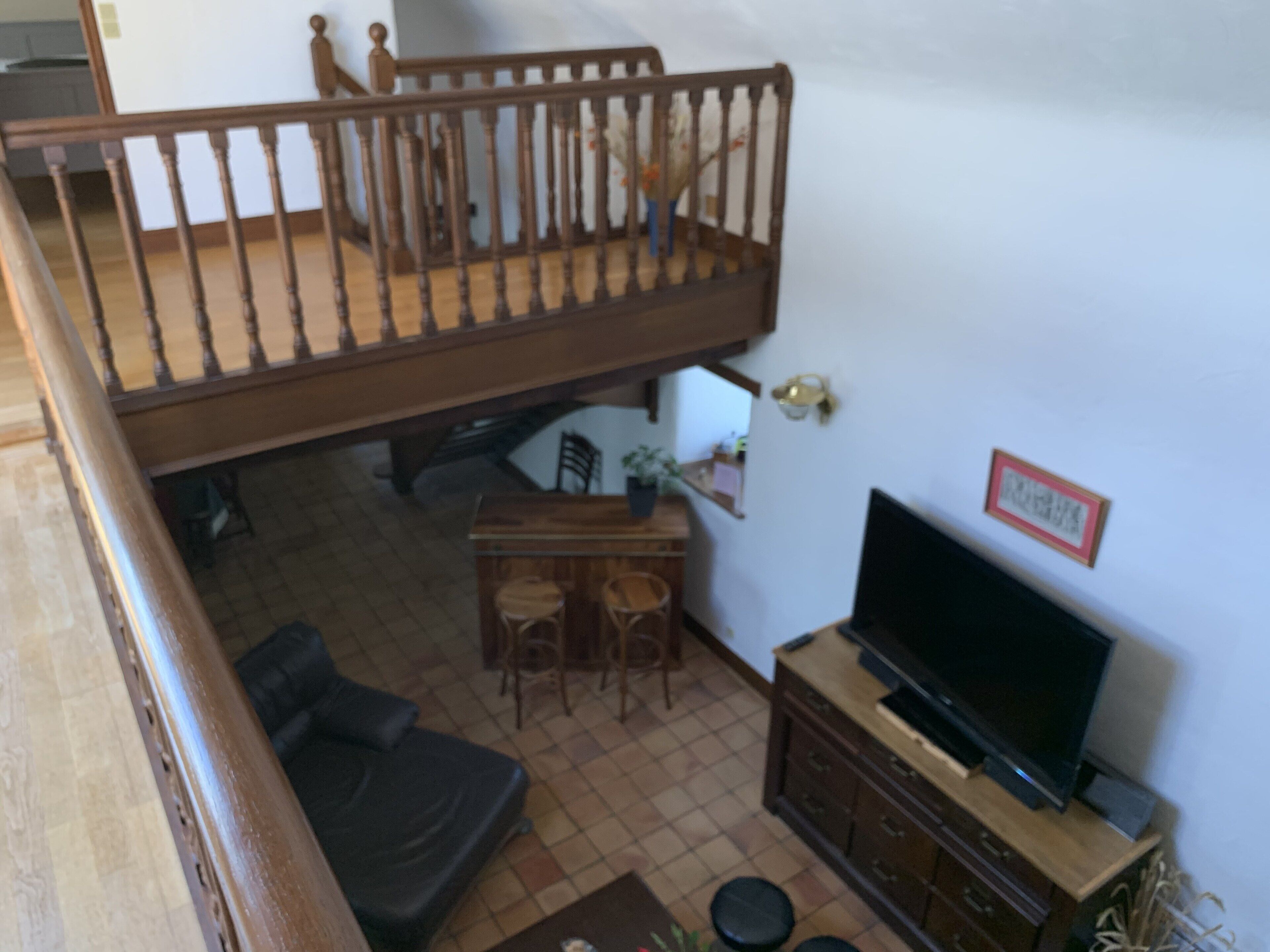 Una sala de estar con una escalera de madera, un televisor, una mesa de comedor con sillas y un sofá.