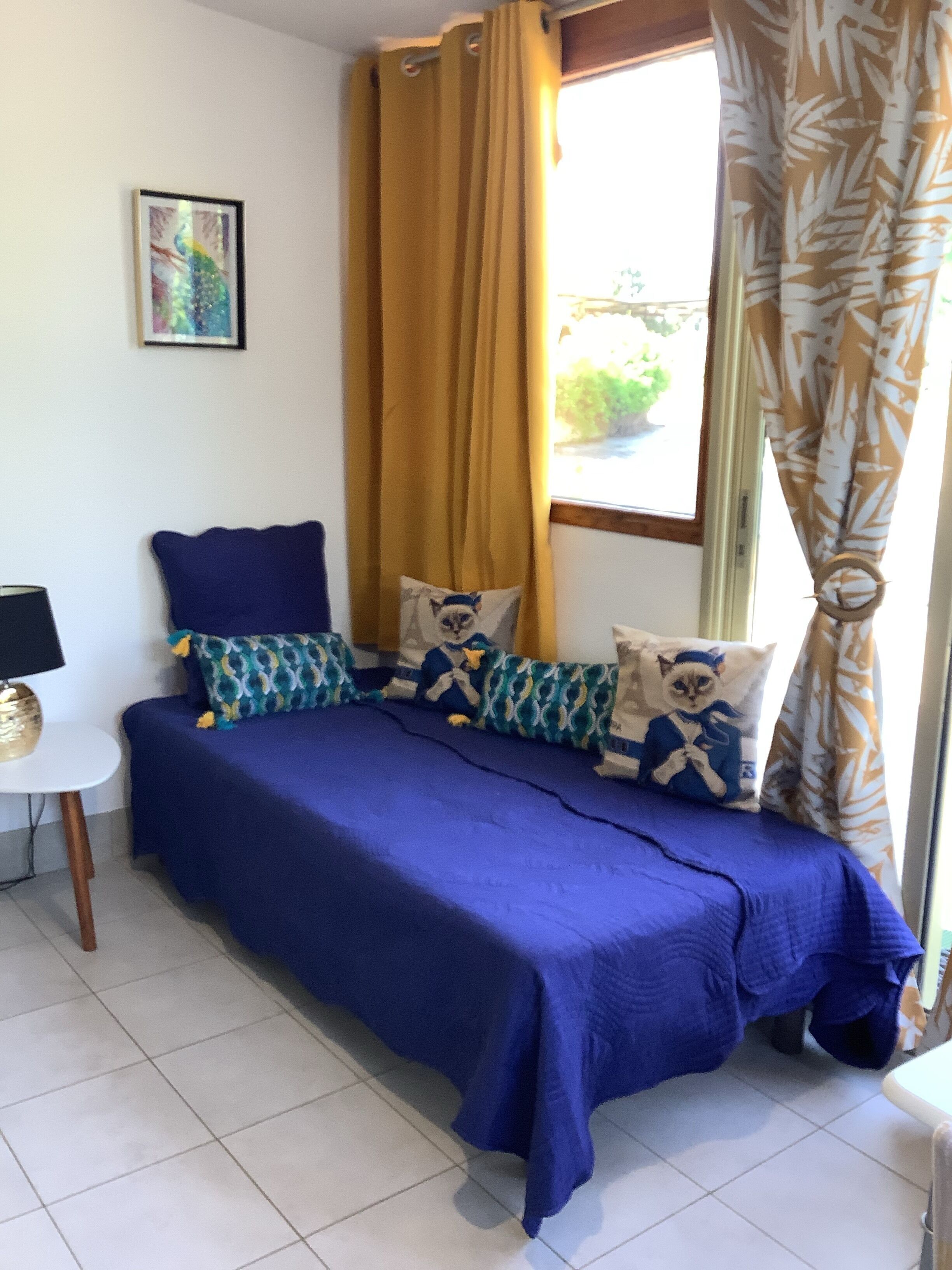 A bedroom with a bed, pillows, a small table, and a window with curtains.