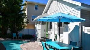 A backyard with a swimming pool, a patio table with chairs, and a blue umbrella. - Welcome to Beach Basket – Your Seaside Retreat!" (Anna Maria)