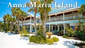 A hotel with a two-story structure, a covered outdoor seating area, and a sign for 'Olive Oil Outlets'. - Welcome to Beach Basket – Your Seaside Retreat!" (Anna Maria)