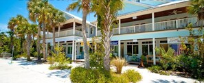 A hotel with a two-story structure, a covered outdoor seating area, and a sign for 'Olive Oil Outlets'.