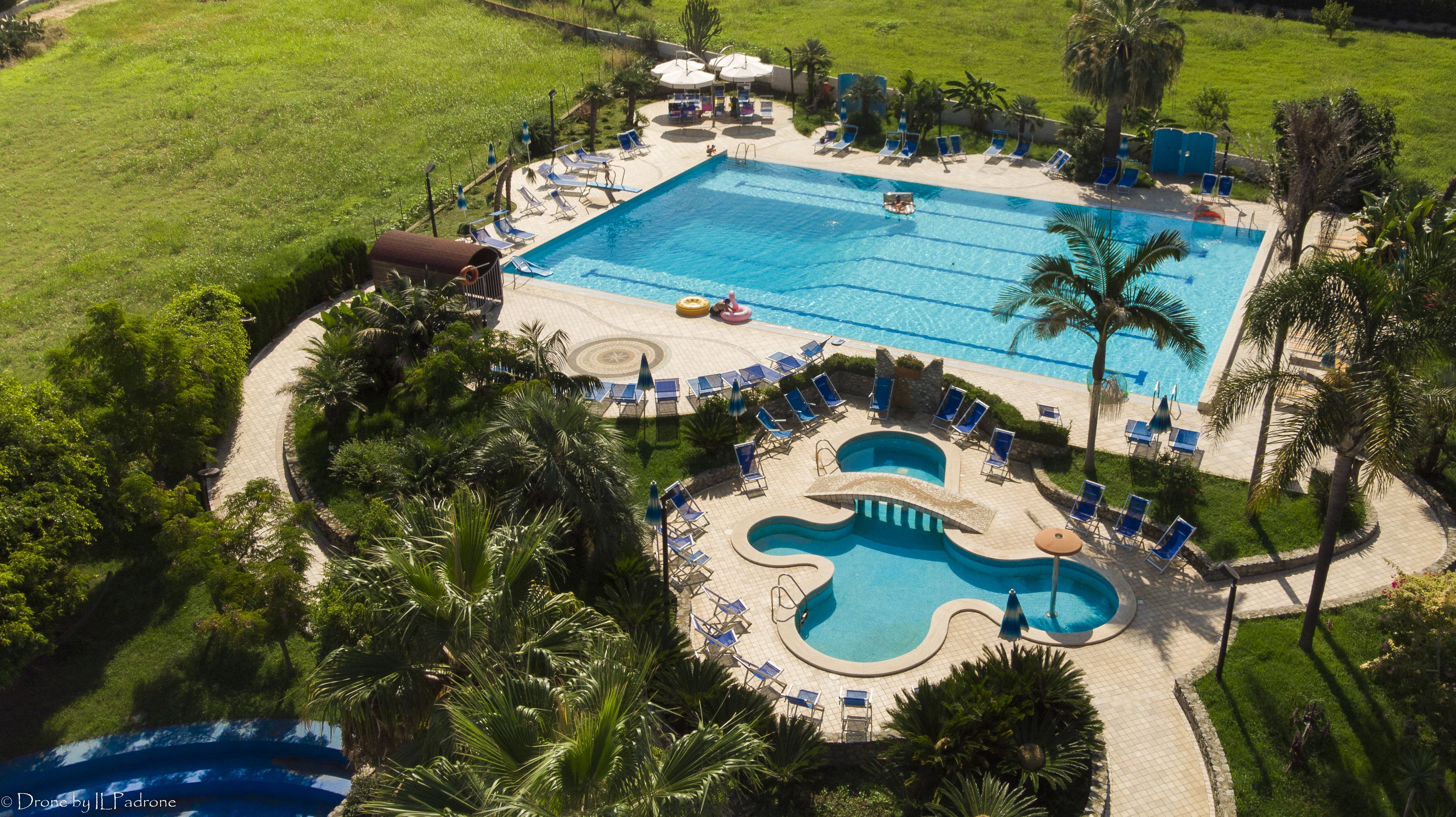 Une grande piscine divisée en plusieurs zones, entourée de chaises longues et de parasols.