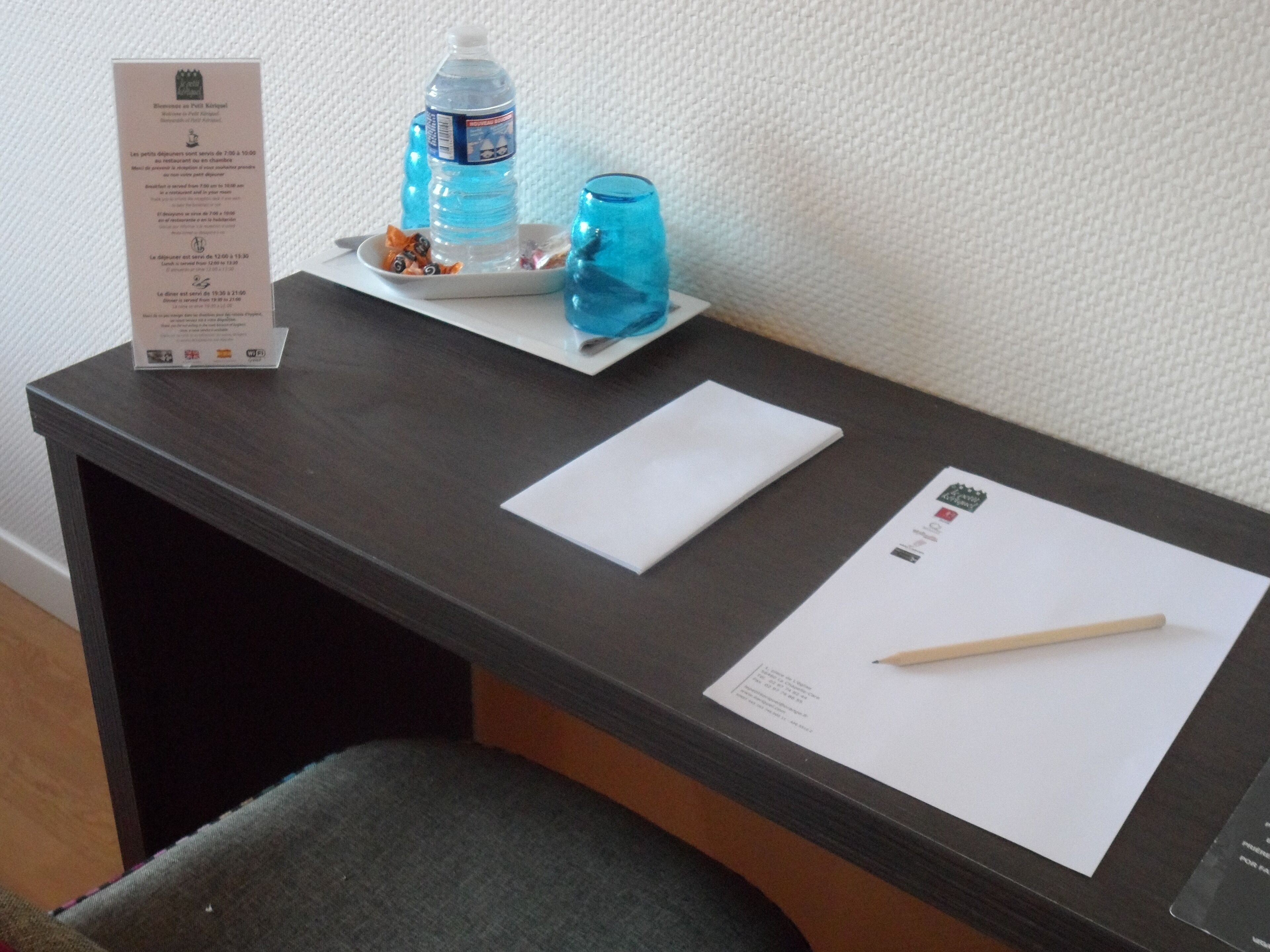 Een hotel receptie met een menukaart, een waterfles, een glas, een notitieboekje en een pen.