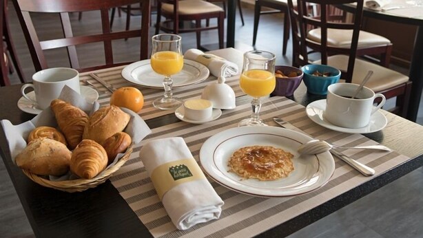 Desayuno con cruasanes, zumo de naranja, café y un bol de fruta.