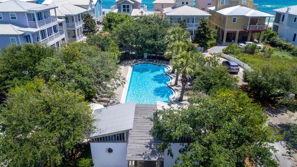 Un resort con piscina rodeado de exuberante vegetación y propiedades frente a la playa.