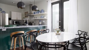 Una cocina moderna con una isla central, taburetes de bar y una mesa de comedor con sillas.