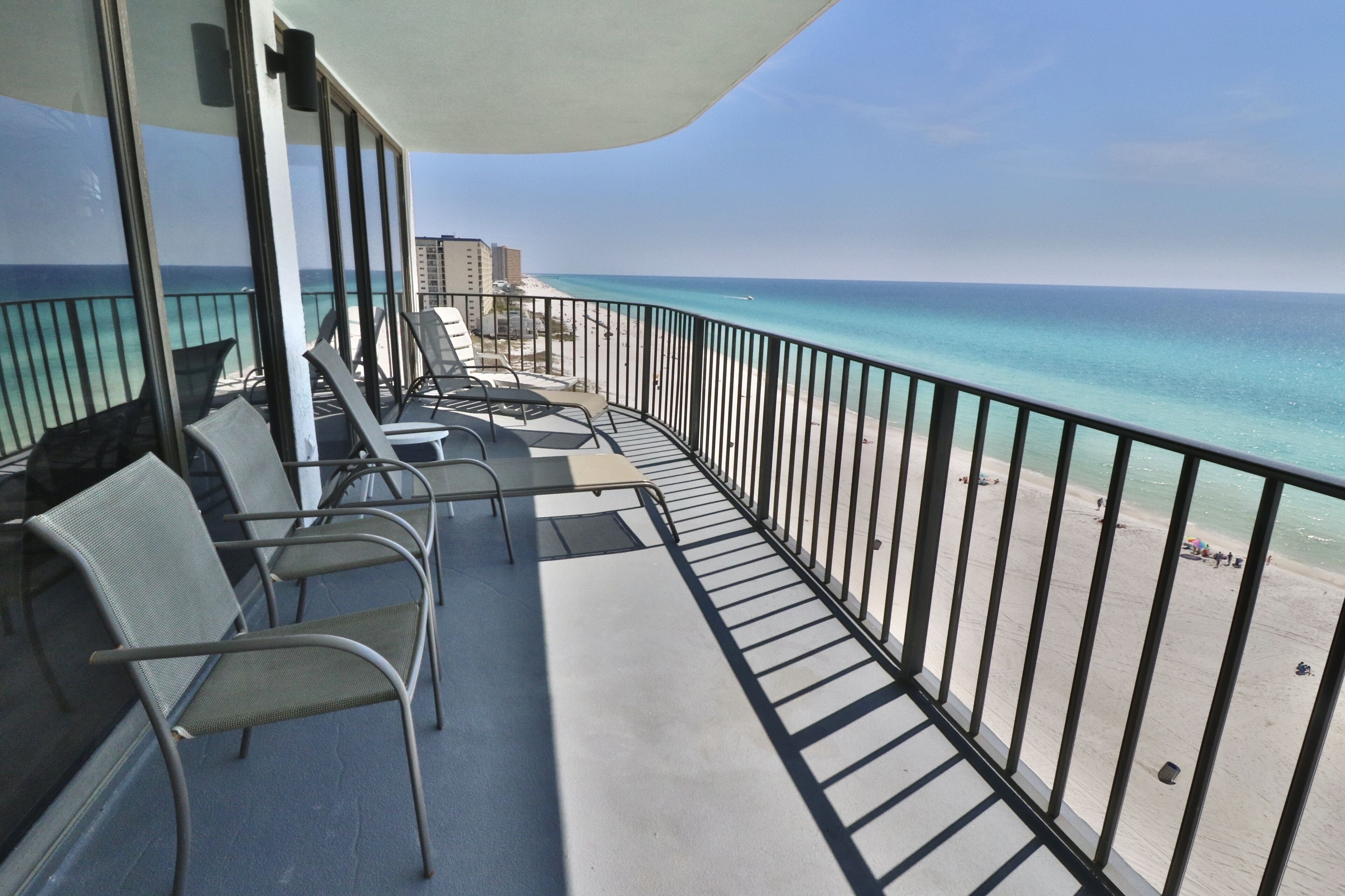 Ein Balkon mit Stühlen und einem Tisch, mit Blick auf einen Strand und freier Sicht auf den Ozean.