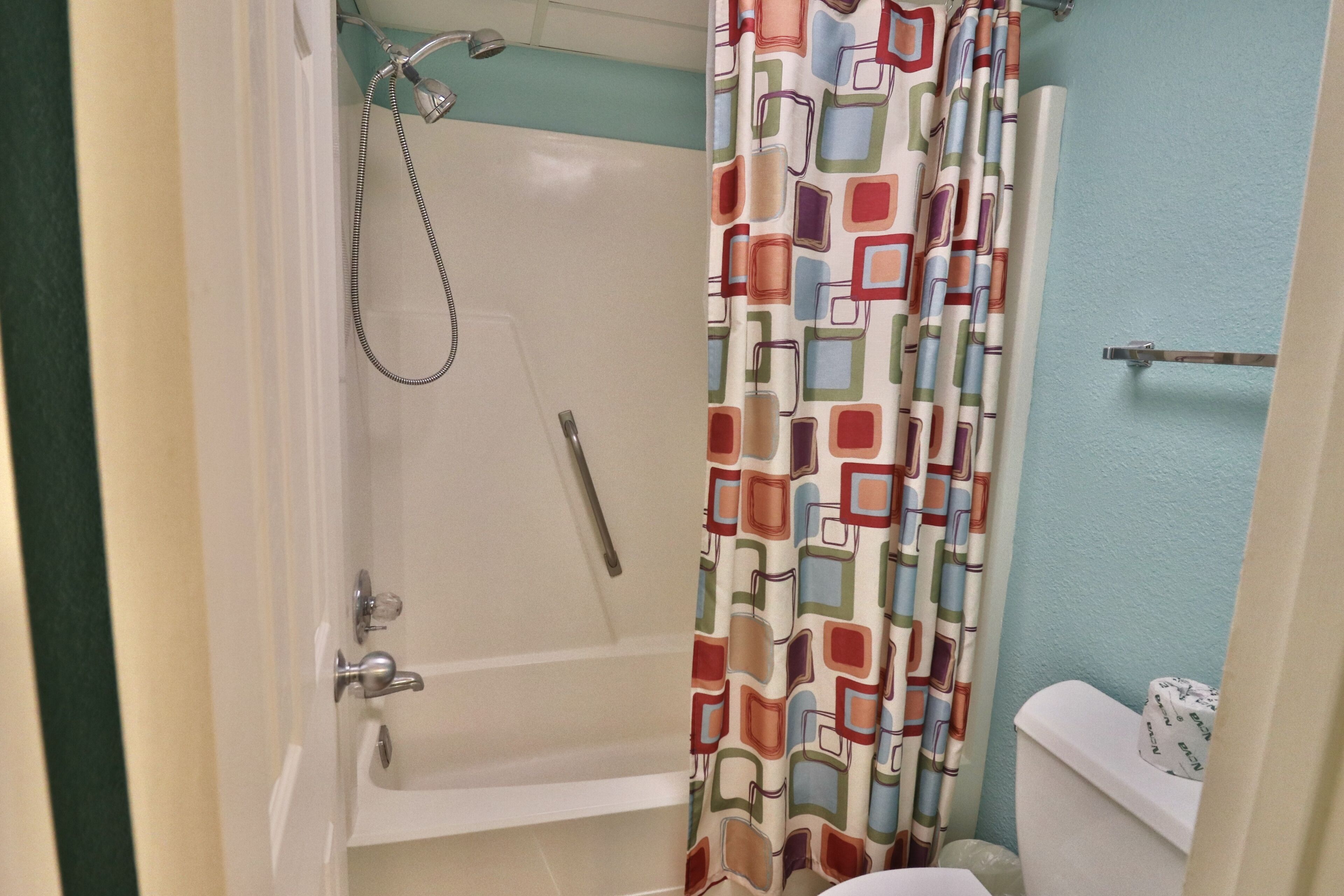 A bathroom with a bathtub, shower, and toilet.