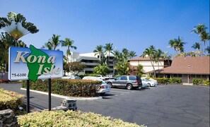 A parking lot with a sign for Kona Isle, surrounded by palm trees and buildings. - Budget Friendly, starting at 150:00 Per. night  waterfront complex. (Kailua-Kona)
