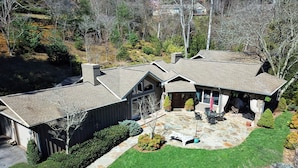 A two-story house with a stone patio, a covered outdoor seating area, and a well-maintained lawn. - Luxury Home in Laurel Ridge Country Club Community (Waynesville)