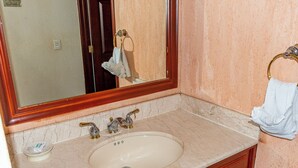 A bathroom with a marble sink, two faucets, a mirror, and a towel ring with a towel. - Sonoran Spa W403 - 2 BR Next to the Pool, High Speed Wi-Fi - Beachfront Upper Floor Luxury Condo (Puerto Peñasco)