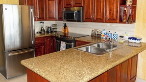A kitchen with granite countertops, stainless steel appliances, wooden cabinets, and a double sink. - Sonoran Spa W403 - 2 BR Next to the Pool, High Speed Wi-Fi - Beachfront Upper Floor Luxury Condo (Puerto Peñasco)
