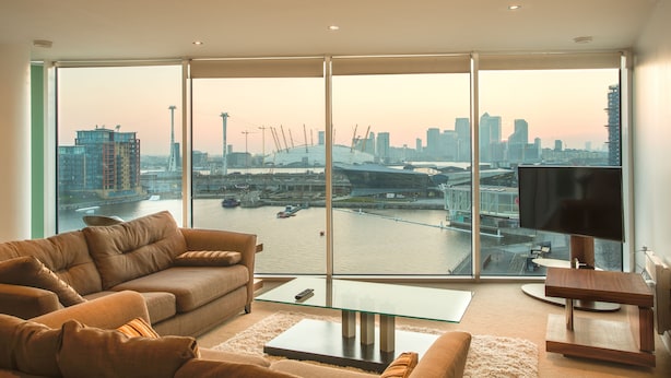A modern living room with a large window offering a city view, a sofa, a coffee table, and a TV stand.