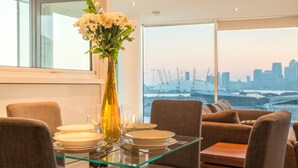 A dining area with a glass table, chairs, and a vase of flowers.