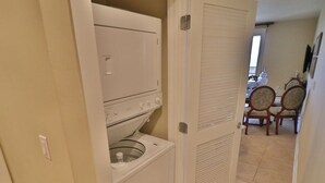 A laundry room with a washer and dryer, a dining area with chairs, and a closed door.