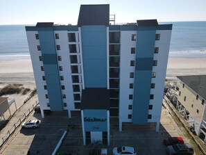 Un hotel de varios pisos con un llamativo letrero de 'Shalimar', situado cerca de una playa.