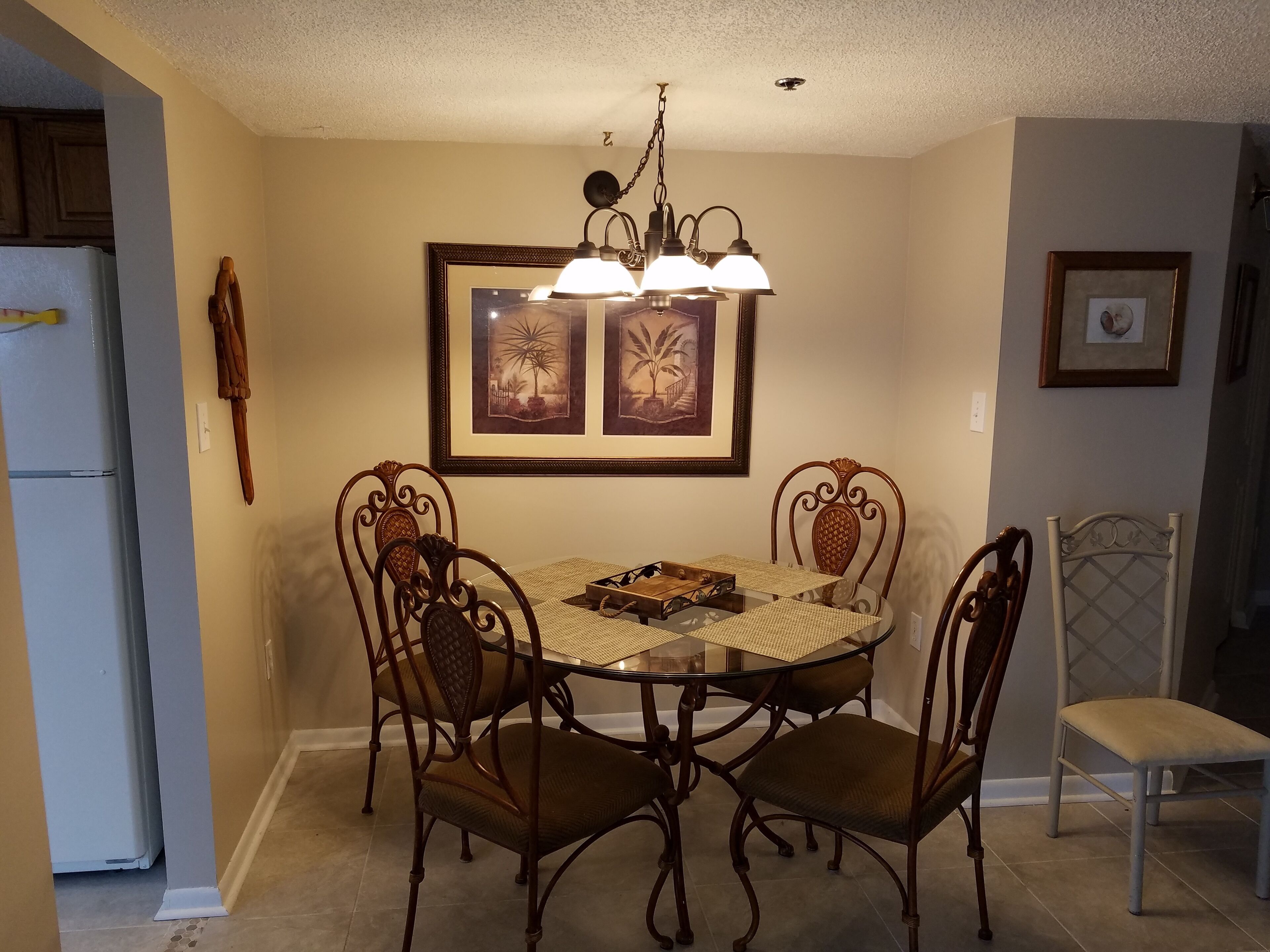 A dining area with a round table, four chairs, and a chandelier.