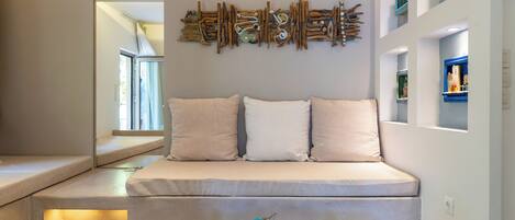 A modern living room with a sofa, a glass coffee table with fruit, and a wall art piece.
