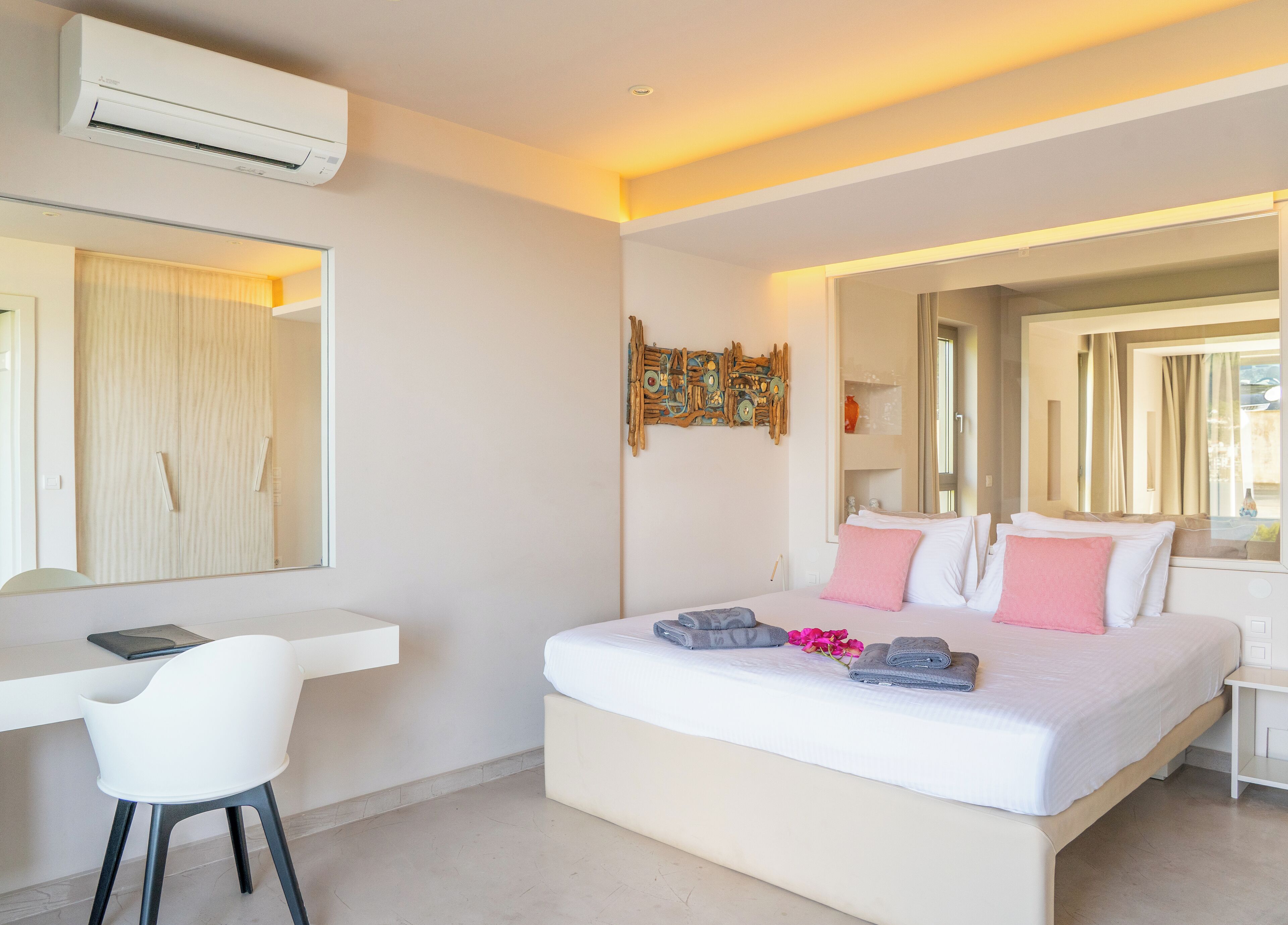 A modern bedroom with a large bed, a desk, and a chair.