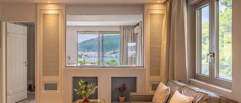 Uma sala de estar moderna com um sofá, uma mesa de centro de vidro e vista para uma paisagem montanhosa através de grandes janelas.