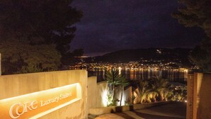 A nighttime view of a coastal area with a sign for "Core Luxury Suites" indicating a hotel or resort. - Core Luxury Suites (Skiathos)