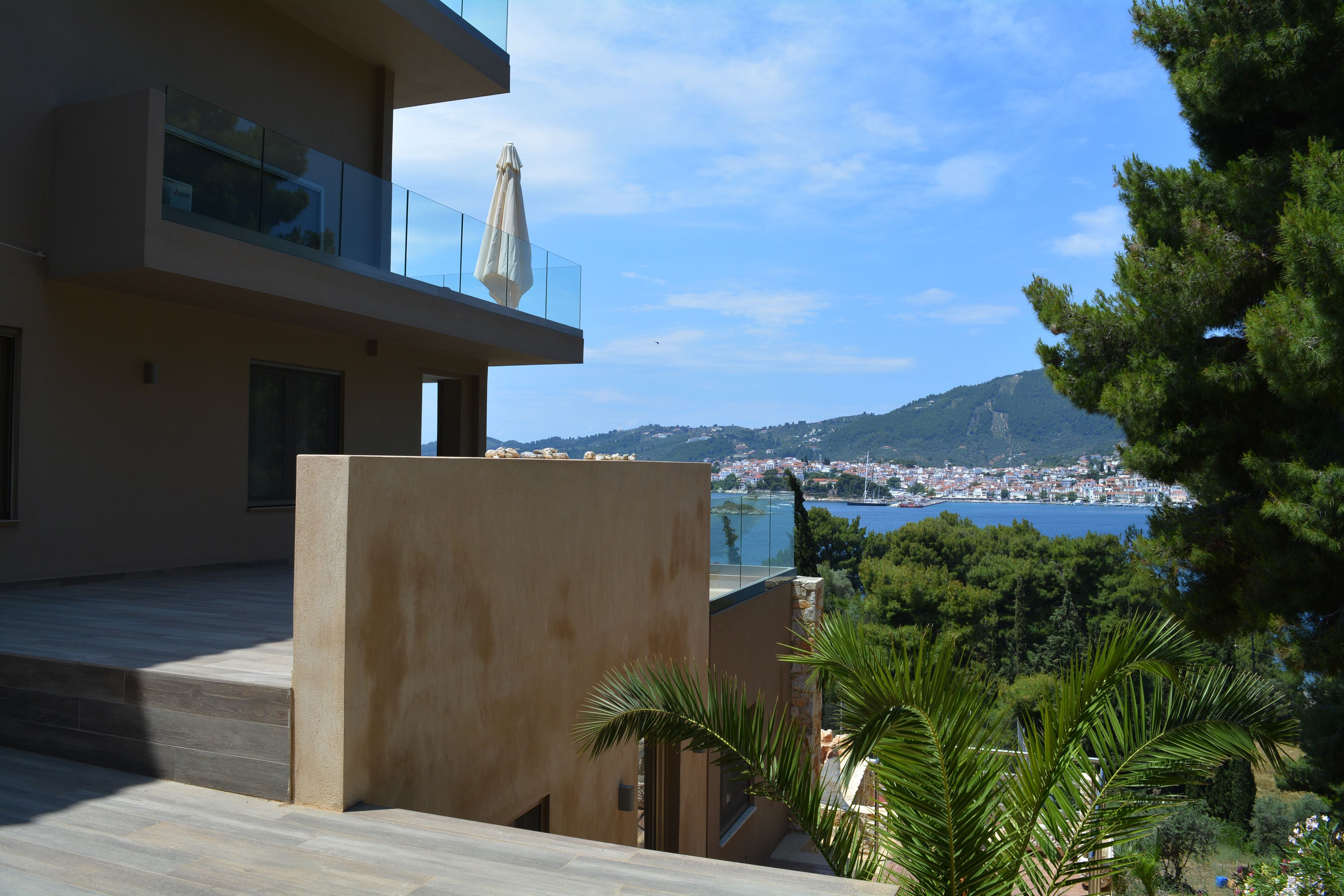 A modern building with a balcony overlooking a coastal town and a body of water.