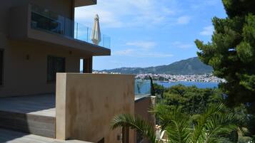 A modern building with a balcony overlooking a coastal town and a body of water.