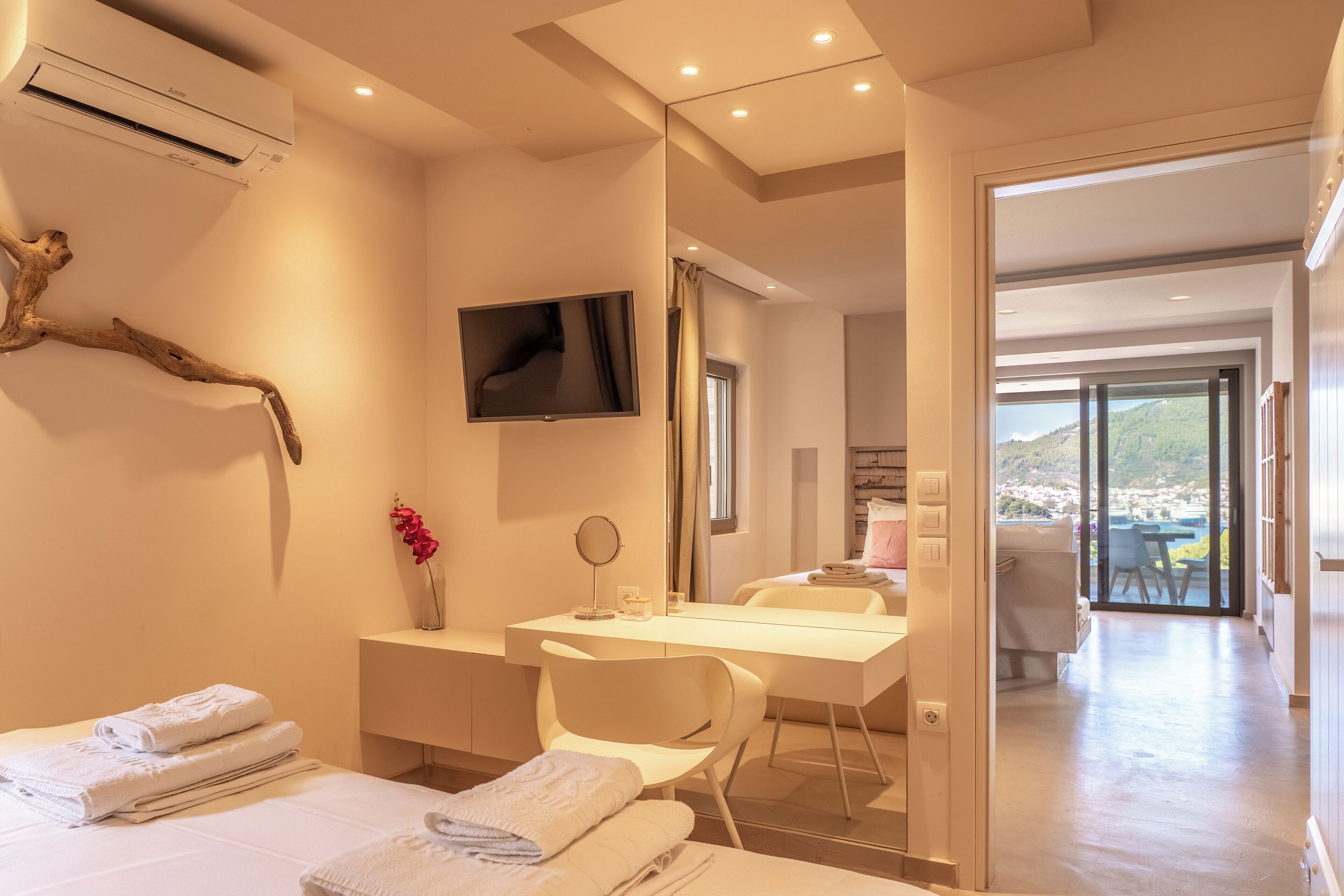 A modern hotel room with a bed, a desk, a TV, and a view of the outside.