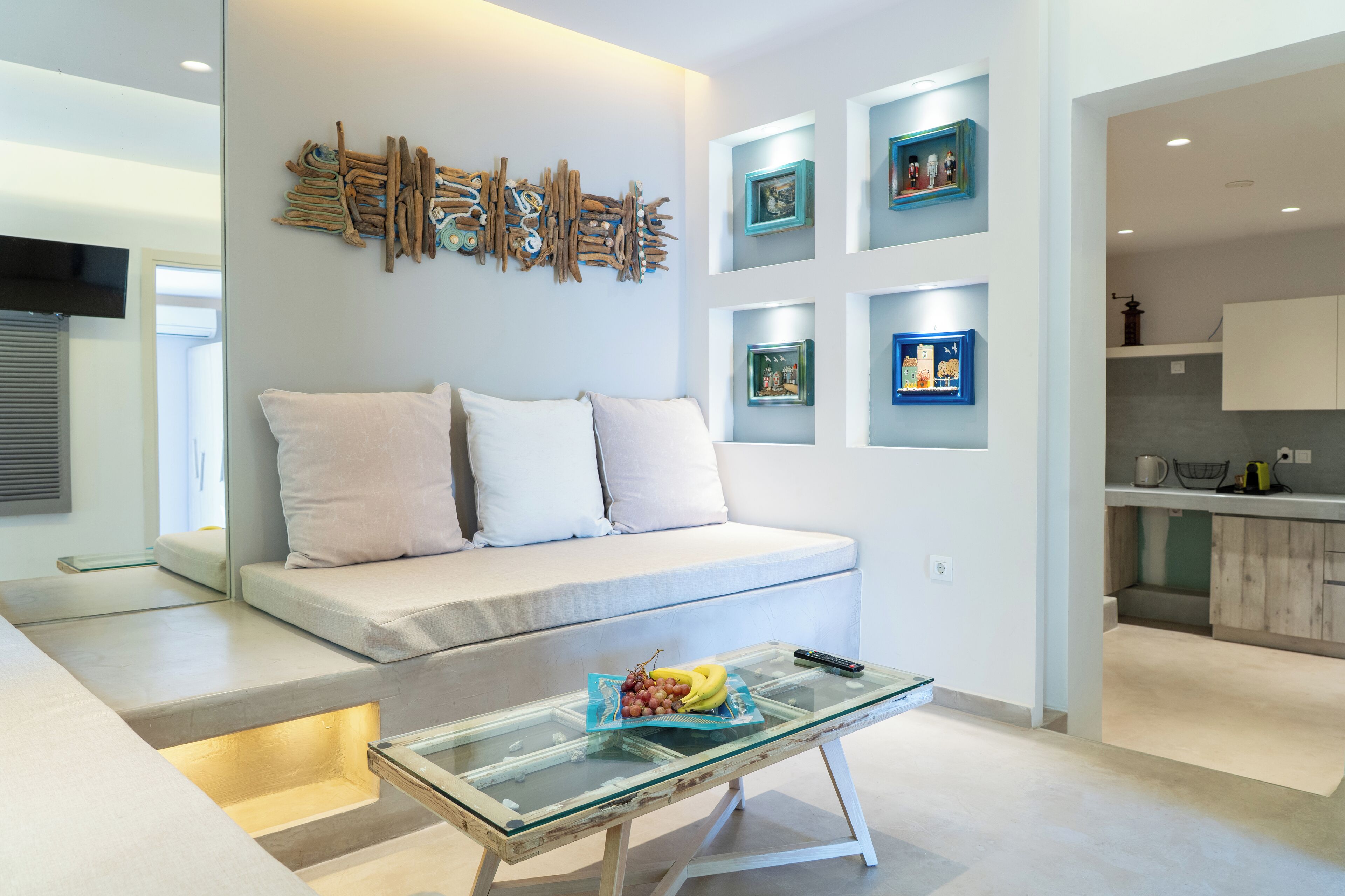 Una sala de estar moderna con una mesa de centro de vidrio, un sofá blanco y una obra de arte colgada en la pared.
