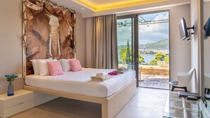 A modern bedroom with a large bed, a glass door leading to a balcony, and a mounted TV. - Core Luxury Suites (Skiathos)