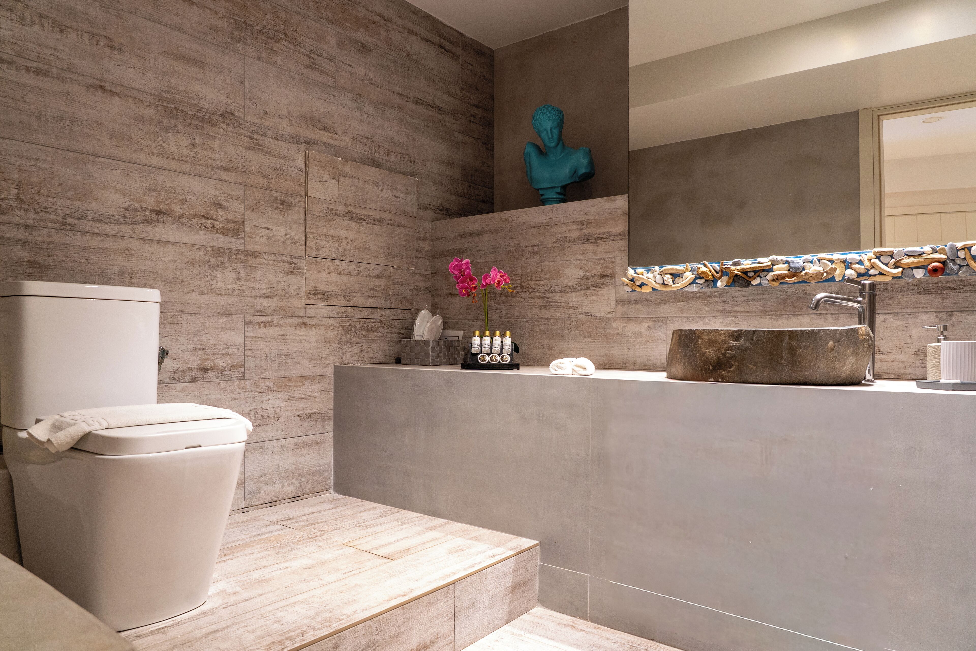 A modern bathroom with a toilet, a sink, and a decorative sculpture.