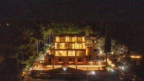 A multi-story building with a well-lit entrance and a visible staircase leading to the upper levels. - Core Luxury Suites (Skiathos)