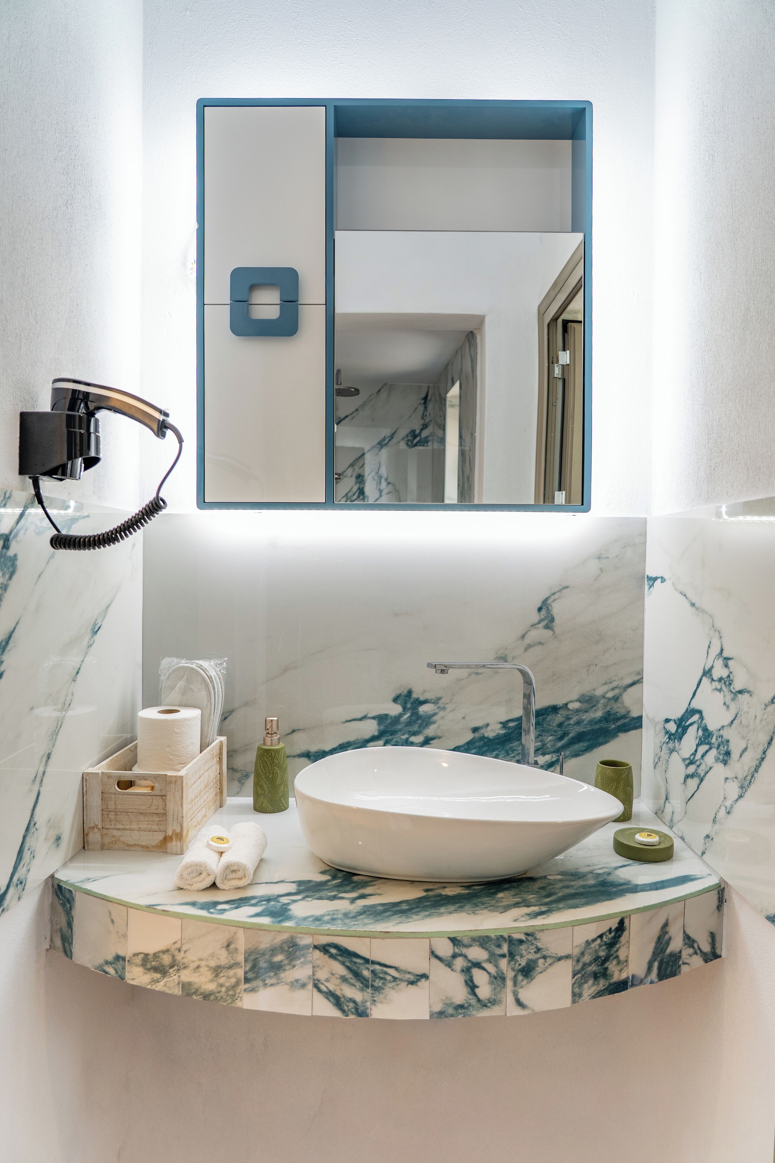A bathroom with a marble sink, a mirror, and a towel rack.