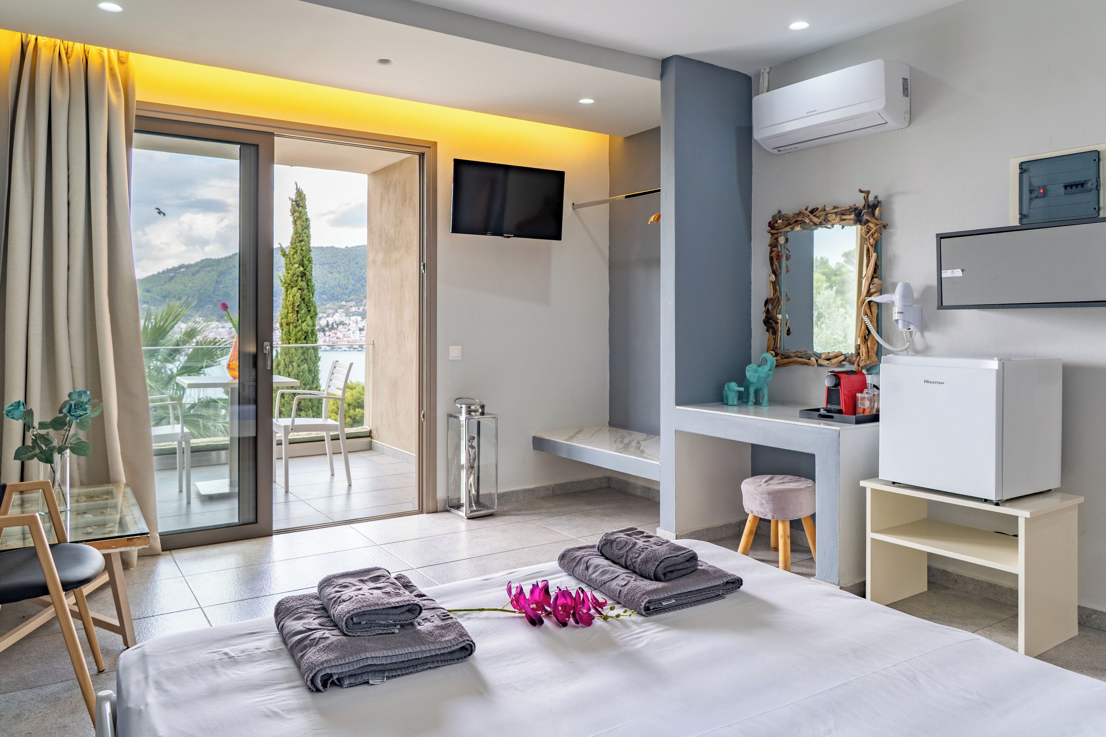 A modern hotel room with a bed, a desk, a television, and a view of the outdoors.