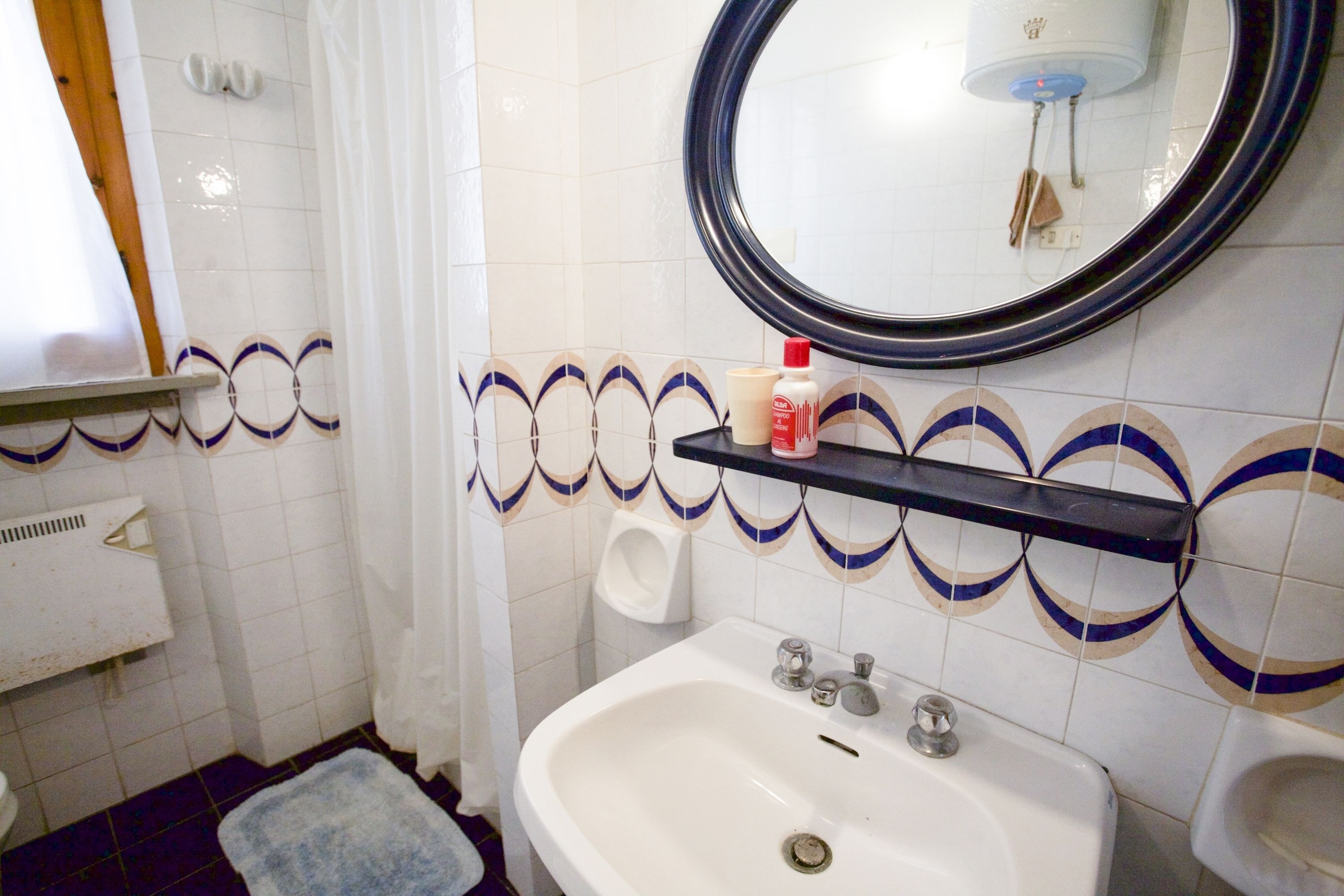 Ein Badezimmer mit einem weißen Waschbecken, einem Spiegel, einem Handtuchhalter und einer Seifenspender.