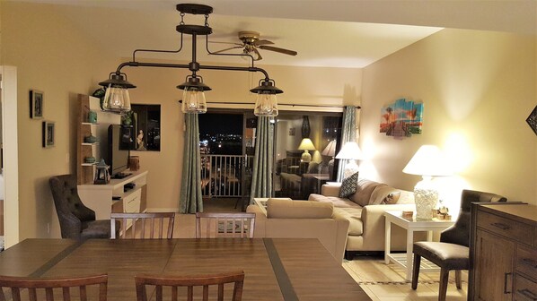 A living room with a dining area, a ceiling fan, and a view of the balcony. - Penthouse w/ Gulf & Intracoastal Views-Steps to Beach!  (Redington Shores)