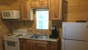 A compact kitchen with wooden cabinets, a microwave, a stove, a sink, and a refrigerator. - Cabin #3, NASHVILLE, Memphis, Kentucky Lake, Birdsong , Loretta Lynns, Paris Tn (Camden)