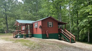 A rustic cabin with a porch, a staircase, and a gravel driveway surrounded by trees. - Cabin #3, NASHVILLE, Memphis, Kentucky Lake, Birdsong , Loretta Lynns, Paris Tn (Camden)