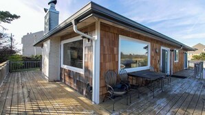 Une maison moderne dotée d’une terrasse, de grandes fenêtres et d’une cheminée.