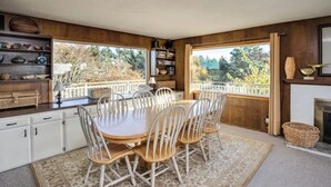 Un coin repas avec une table ronde et des chaises, une bibliothèque et une vue sur l’extérieur.