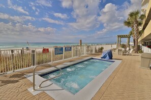 A pool area with a view of the beach, a covered seating area, and a palm tree. - Emerald Isle Beach Front Condo. Free Beach Chairs and Dedicated Parking Spot (Panama City Beach)