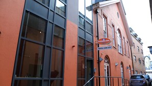Um edifício com grandes janelas, uma placa com o nome Blackmore Court Hostel Cork City e um carro estacionado.