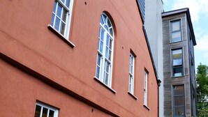Um edifício vermelho com janelas emolduradas por branco e um banco na frente.