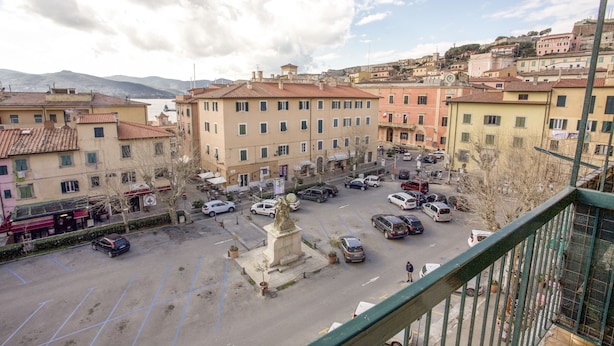 Une place de ville avec des bâtiments, une statue et des voitures garées.