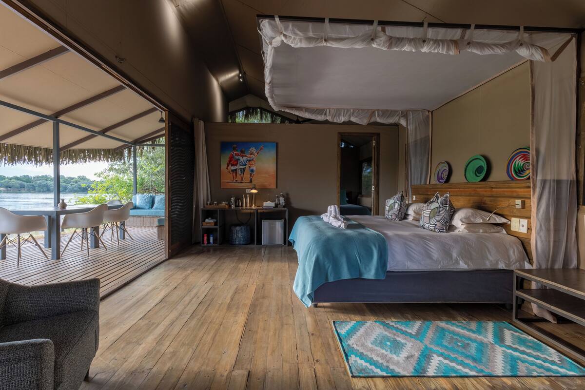 A bedroom with a large bed, a desk, and a view of a lake.