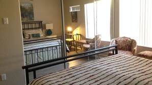 A bedroom with a large bed, a chair, a desk, and a mirror. - Old Town Desert Retreat (Scottsdale)