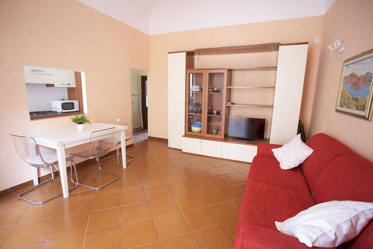 A compact living space with a kitchenette, a dining area, and a red sofa.
